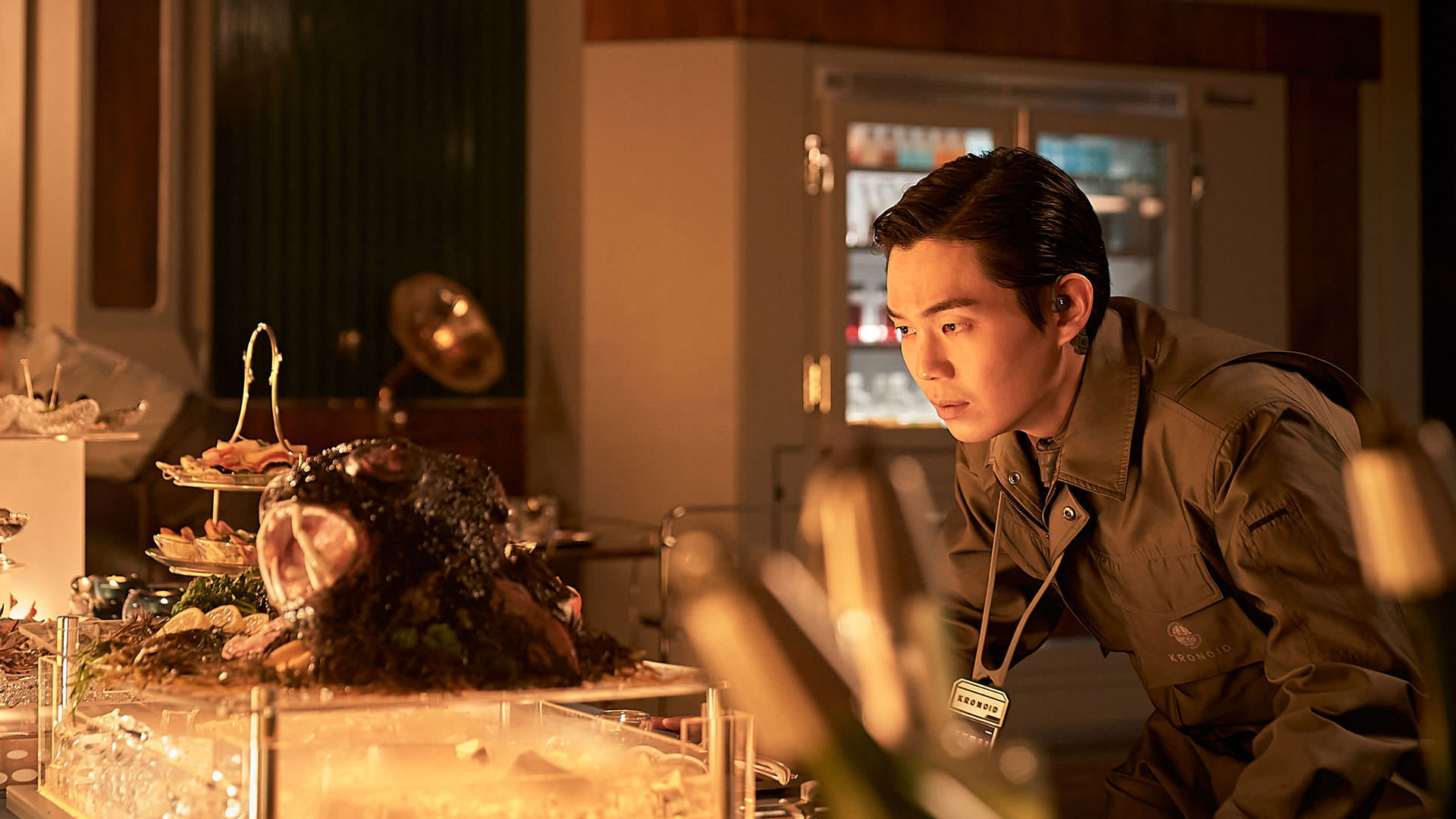 ریو کیونگ سو در حال نگاه کردن به میزی از غذاهای مجلسی در نمایی از فیلم جونگ ای به کارگردانی یون سانگ-هو
