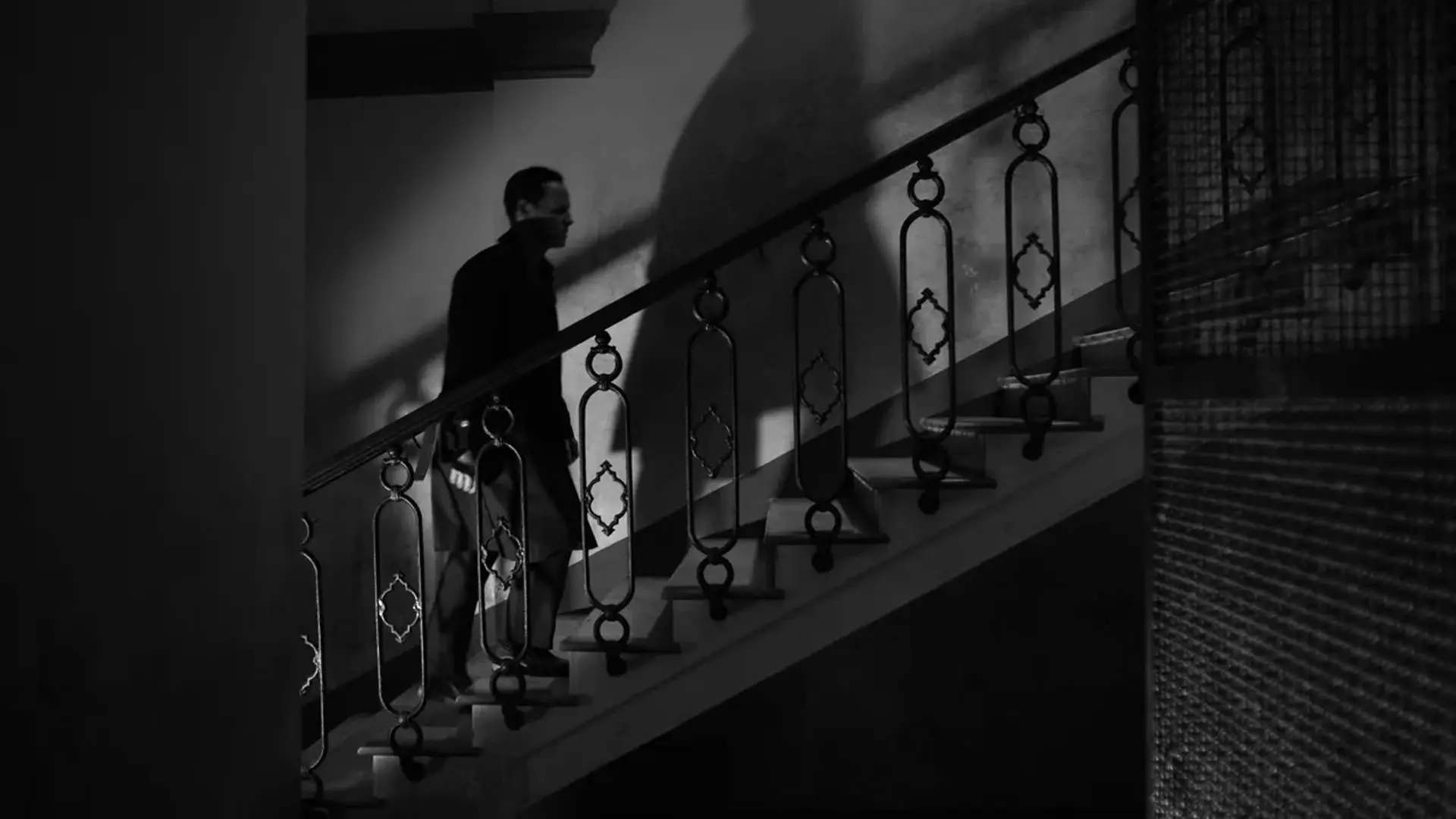 اندرو اسکات در حال بالا رفتن از یک پله در حالی که سایه بزرگش پشت سرش دیده می‌شود در عکسی سیاه و سفید از سریال ریپلی به کارگردانی استیون زایلیان